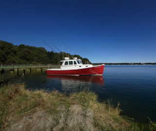 Red boat on water showcasing Wynne sliding windows.
