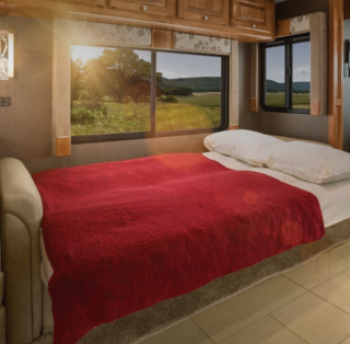 A bed inside of a motorhome showcasing the custom sliding windows.